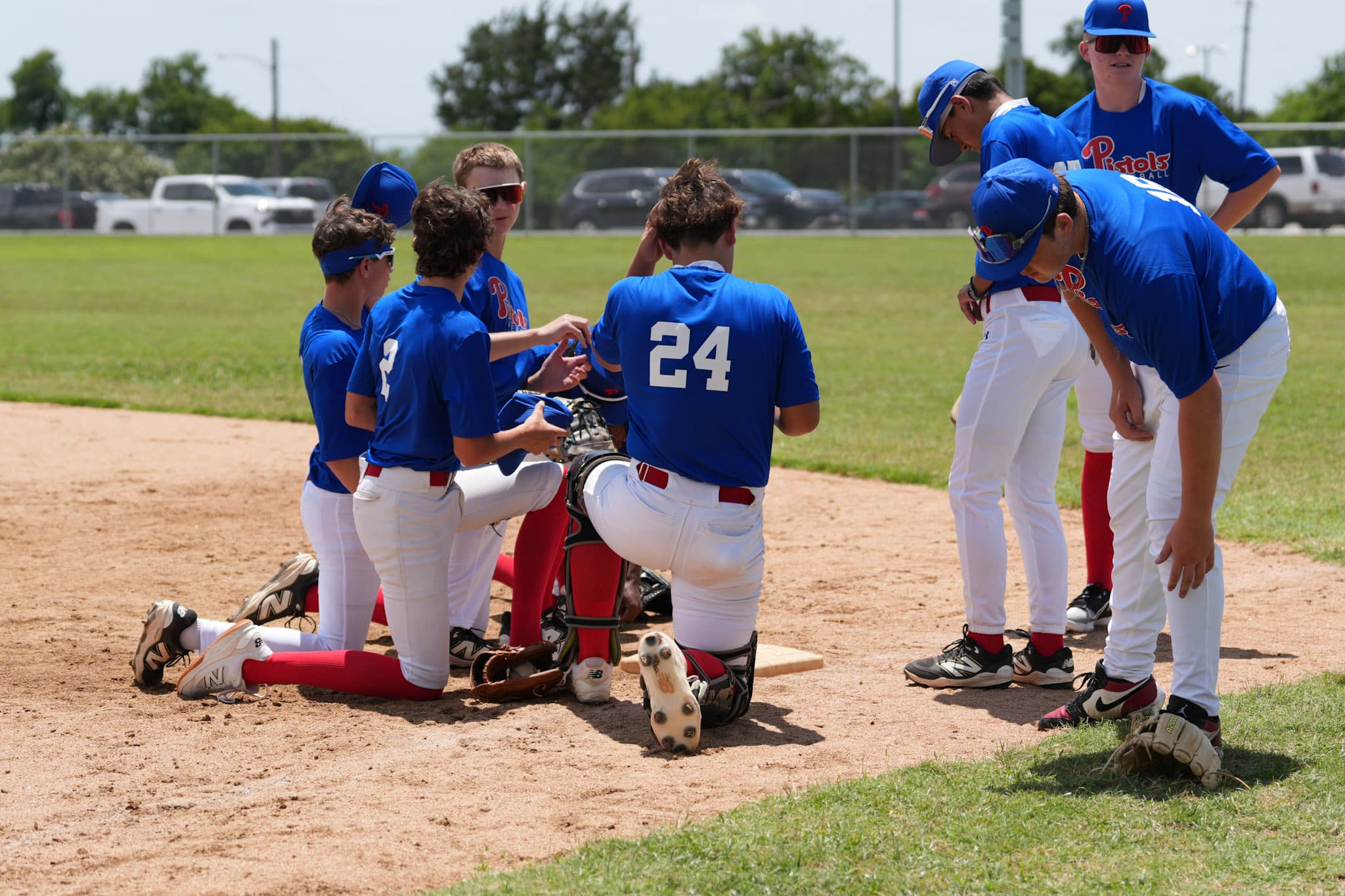 A coach huddled with his team, players kneeling around him